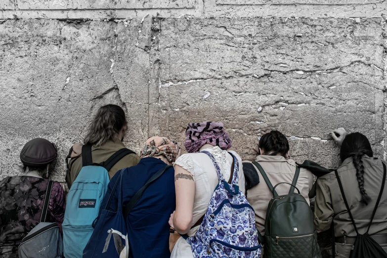 a group of people standing next to a stone wall, a photo, by Micha Klein, the western wall, uhd candid photo of dirty, her back is to us, 😭🤮 💔