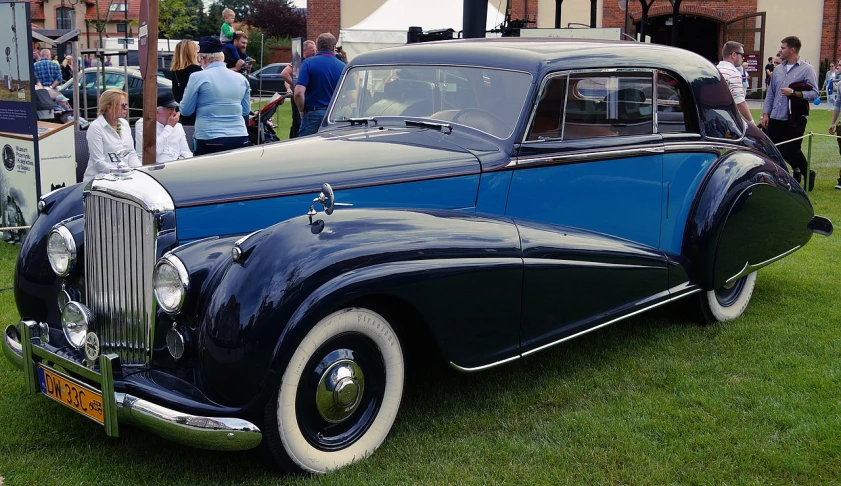 a blue and black car parked on top of a lush green field, by David Simpson, flickr, bauhaus, bentley, coronation, 1 9 4 0's, vintage - w 1 0 2 4