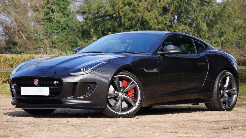 a black sports car parked on a dirt road, renaissance, jaguar, detailed alloy wheels, striking colour, very tasty