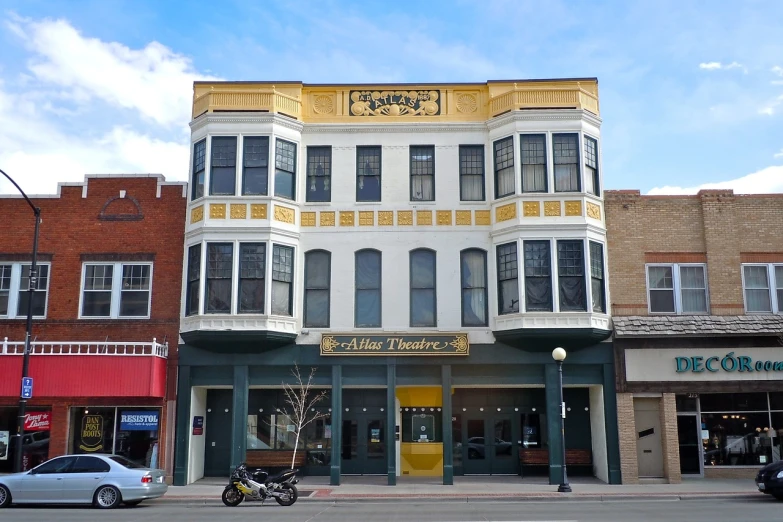 a yellow and white building with a motorcycle parked in front of it, by Susan Heidi, flickr, art nouveau, epic theater, wyoming, view from front, apollo