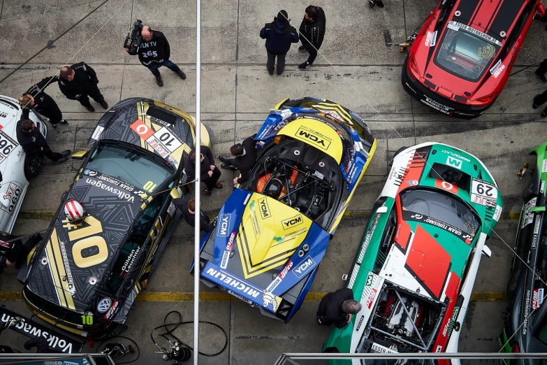 a group of racing cars parked next to each other, by Carlo Martini, nico delort, high camera angle, 😃😀😄☺🙃😉😗, maintenance