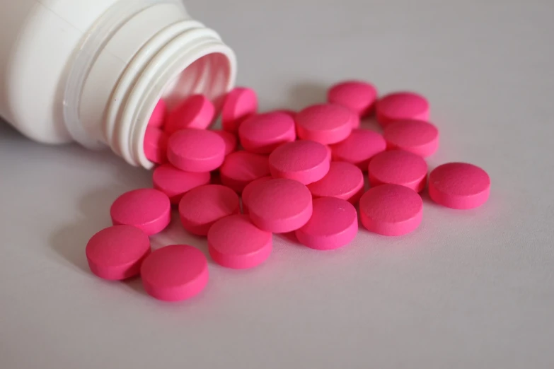 a bottle of pink pills spilling out of it, plasticien, rich deep pink, soft pads, covered in pink flesh, slight blur