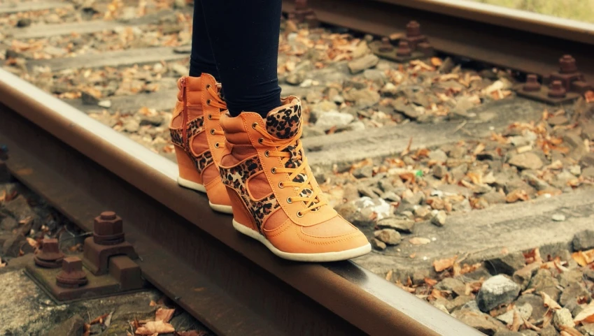 a close up of a person's shoes on a train track, a picture, by Maksimilijan Vanka, orange colors, side view of her taking steps, tiger stripes, beautiful girls