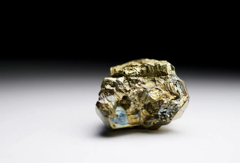 a piece of metal sitting on top of a table, a macro photograph, lump of native gold, highly detailed product photo, strong iridescent light, product introduction photo