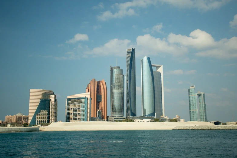 a large body of water with a bunch of tall buildings in the background, hurufiyya, domes, the building is a skyscraper, shaded, in the desert beside the gulf