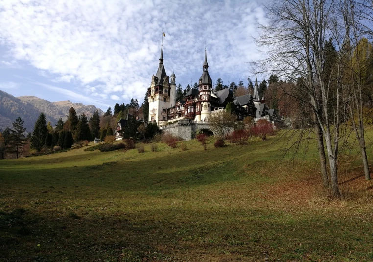 a castle sitting on top of a lush green hillside, a photo, by Hristofor Žefarović, art nouveau, black domes and spires, autum, very very well detailed image, lawn