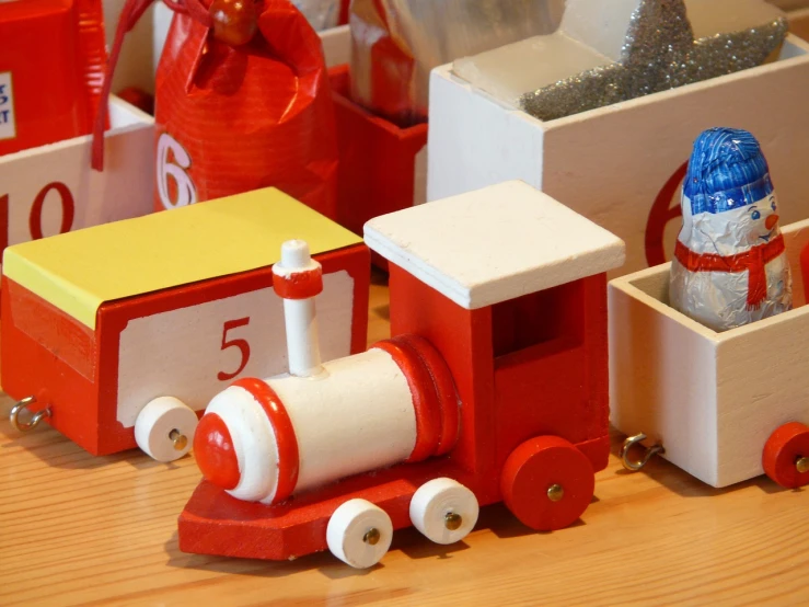 a close up of a toy train on a table, inspired by Rube Goldberg, flickr, figuration libre, red and white color scheme, wooden banks, presents, ƒ/5.6