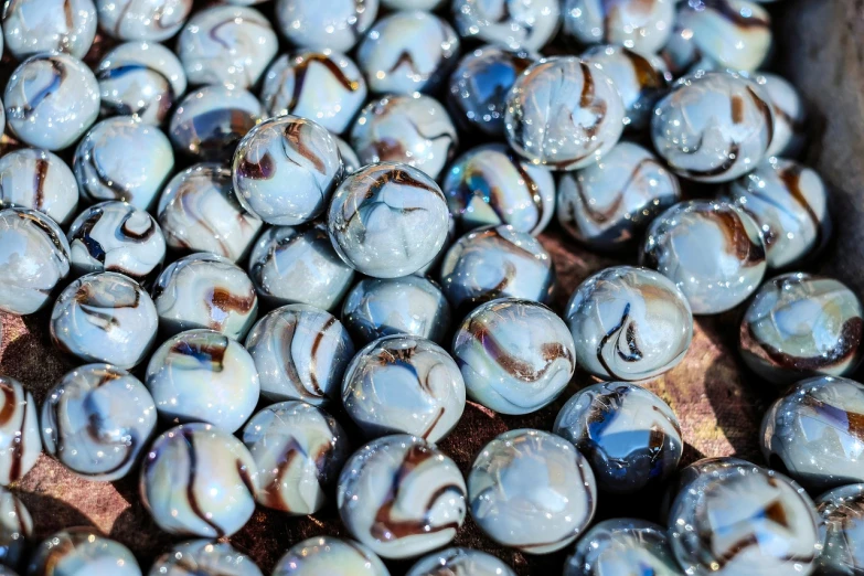 a pile of glass beads sitting on top of a wooden table, a macro photograph, inspired by Quirizio di Giovanni da Murano, reddit, marble background, pale blue, superb detail 8 k, rich marbles