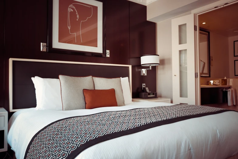 a bed room with a neatly made bed and a picture on the wall, by Lee Loughridge, pexels, maroon metallic accents, orange and black tones, hotel, brown and white color scheme