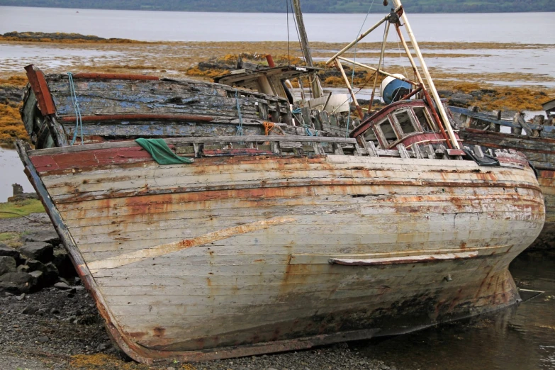 a boat sitting on top of a beach next to a body of water, a portrait, by Edward Corbett, flickr, with damaged rusty arms, skye meaker, detailed zoom photo, some boats