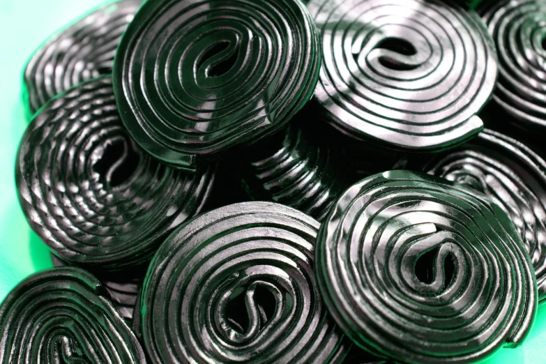 a pile of black candy sitting on top of a green table, a macro photograph, by Harold Elliott, flickr, op art, heated coils, shiny metal, maze, jelly - like texture. photograph