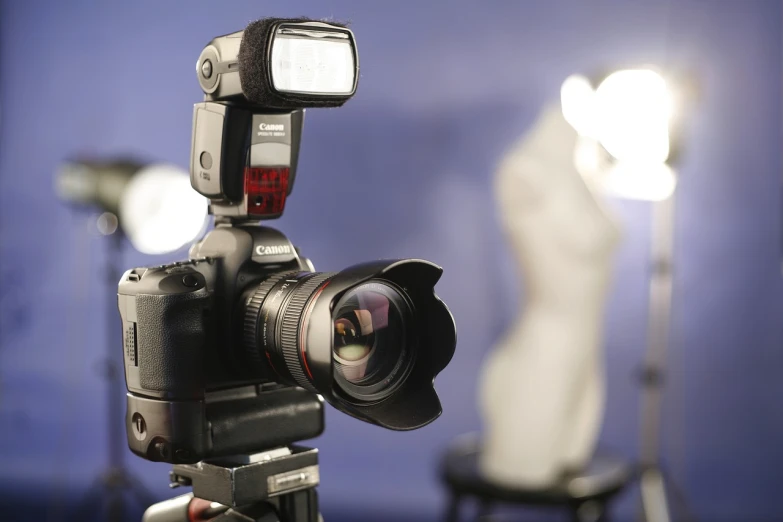 a close up of a camera on a tripod, soft volumetric lights, holding a dslr camera, product photograph, canon 7 d