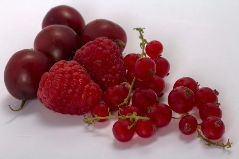 a bunch of grapes and raspberries on a white surface, a still life, by Harry Haenigsen, pexels, romanticism, shot on a 2 0 0 3 camera, red colored, n- 4, magenta