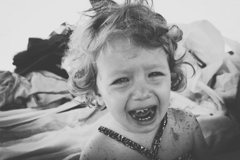 a black and white photo of a toddler crying, a black and white photo, full of sand and glitter, broken teeth, beach, instagram photo