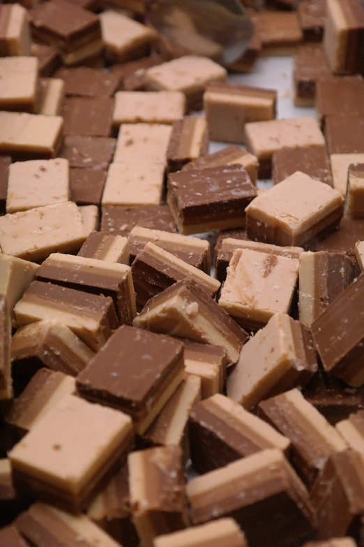 a pile of pieces of chocolate sitting on top of a table, a picture, by Lee Loughridge, squares, cream, two - tone, 15081959 21121991 01012000 4k