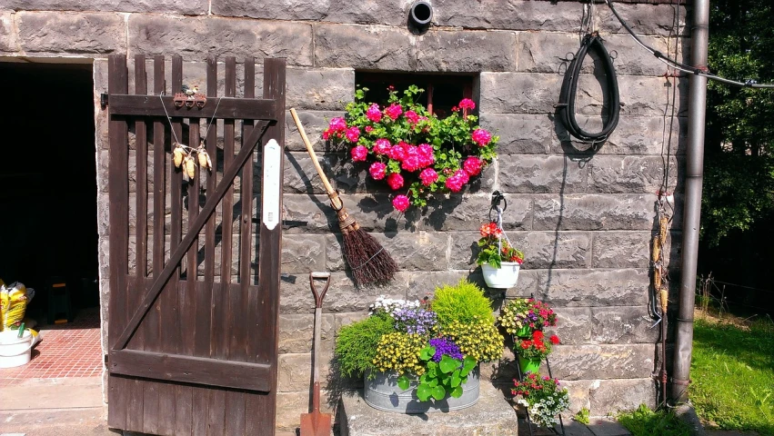 a bunch of flowers hanging on the side of a building, assemblage, marsden, near a stone gate, home display, shepherd's crook