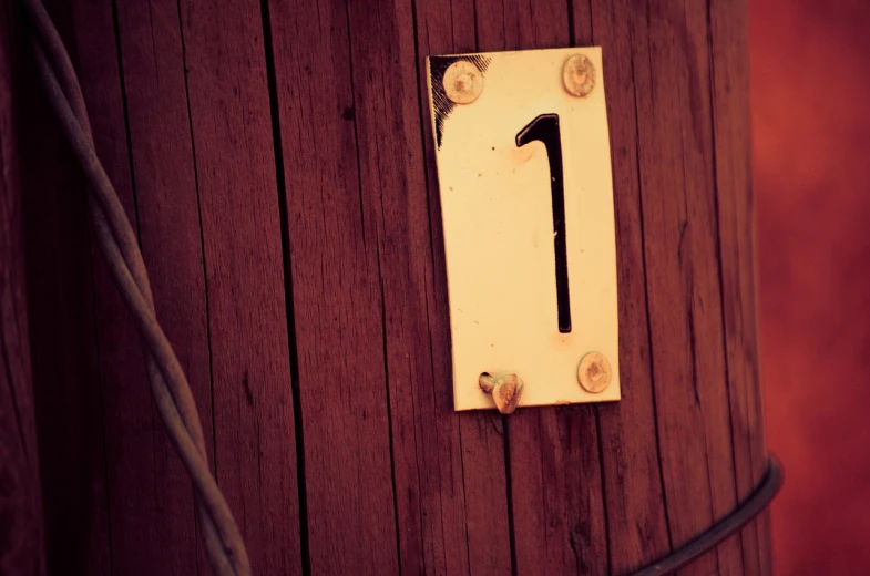 a close up of a wooden pole with a number one on it, by Alexander Robertson, flickr, wooden walls brass panels, cute:2, countdown, grain”