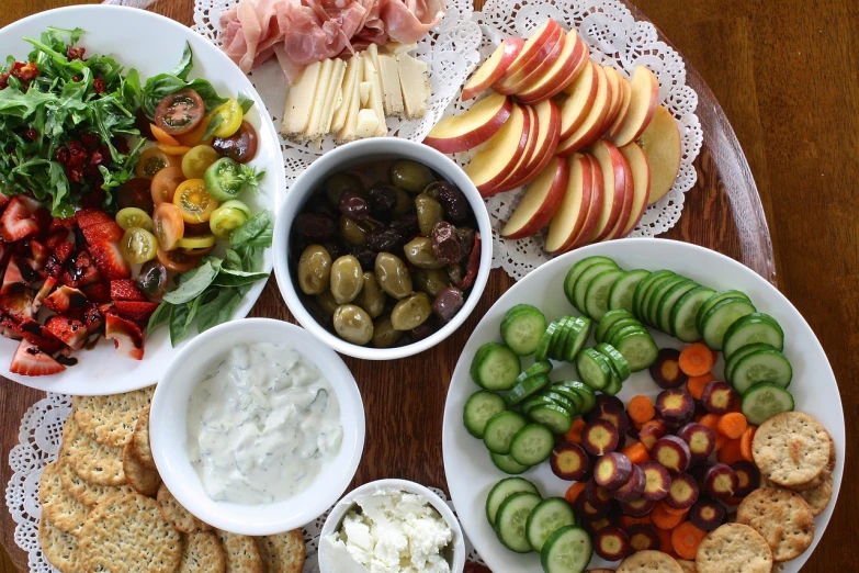 a wooden table topped with plates of food, by Christen Dalsgaard, pexels, olives, veggies, having a snack, unedited