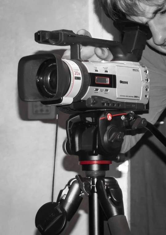 a man standing next to a camera on a tripod, vhs camcorder footage, taken with my nikon d 3, shot on red camera, dslr camera img_4016