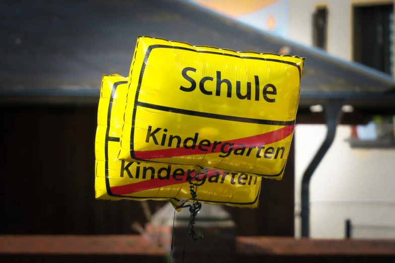 a close up of a street sign with a building in the background, a picture, heidelberg school, baloons, modern very sharp photo, kindchenschema, school bag