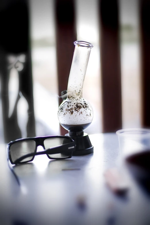 a pair of glasses sitting on top of a table, a tilt shift photo, by Adam Chmielowski, process art, smoking a magical bong, covered with tar. dslr, istock, very accurate photo