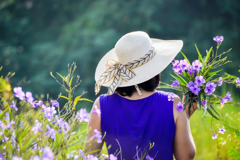 a woman in a hat holding a bunch of flowers, pixabay contest winner, serene field setting, purple color-theme, avatar image, candid photograph