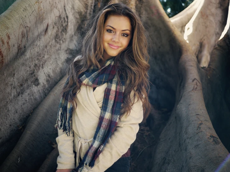 a beautiful young woman standing in front of a tree, tumblr, tartan scarf, mila kunis, warm and gentle smile, teenage vanessa morgan