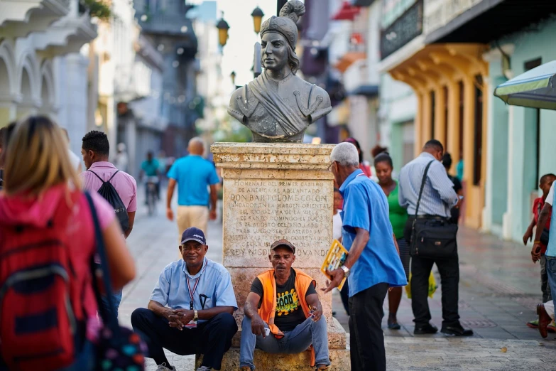 a group of people sitting next to a statue, a statue, by Ken Elias, shutterstock, street art, 30-year-old woman from cuba, 💣 💥, tourist photo, old man