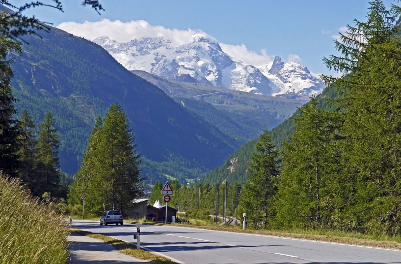 a car that is sitting on the side of a road, by Werner Andermatt, flickr, snow capped mountains, bernini, seen from a distance, a wooden