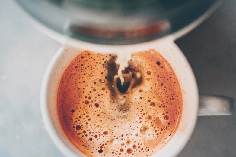 a close up of a cup of coffee, by Karl Buesgen, unsplash, process art, some pouring techniques, vintage color, connection rituals, medium format. soft light