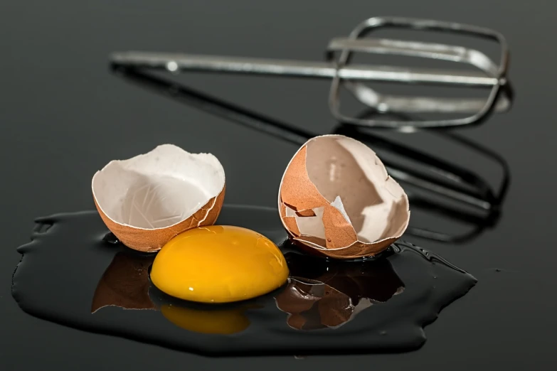 a broken egg sitting on top of a black plate, a still life, by Dietmar Damerau, trending on pixabay, reflection, cake, medical photography, close-up product photo