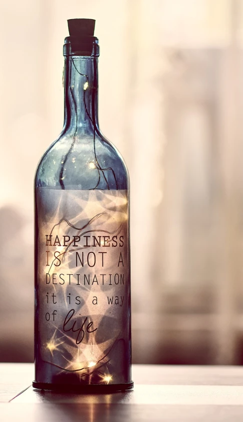 a blue bottle sitting on top of a wooden table, a picture, by Tatiana Hordiienko, tumblr, graffiti, happy lighting, inspirational quote, glass bottle, happiness