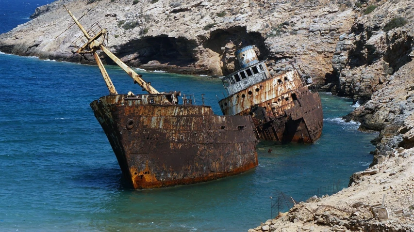 a rusted ship sitting on top of a body of water, a photo, by Richard Carline, greek, front and side view, crumbling, petros