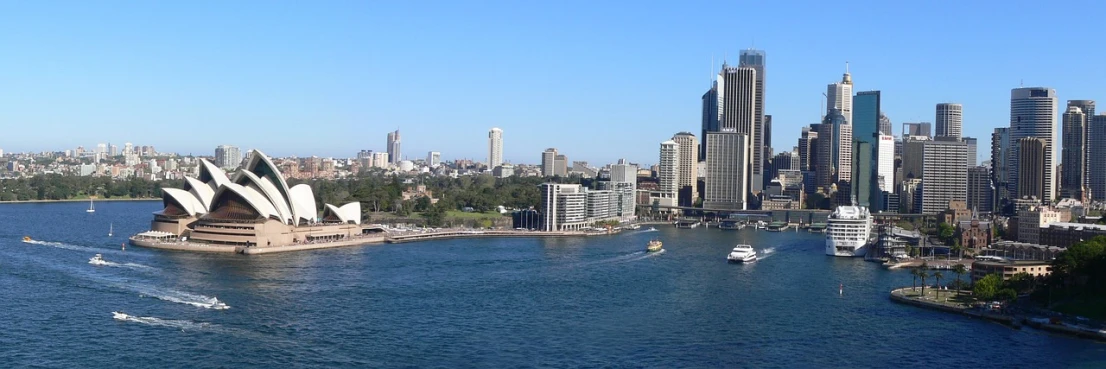 a large body of water with a city in the background, inspired by Sydney Carline, flickr, hurufiyya, wikimedia commons, banner, harbor, sunny day