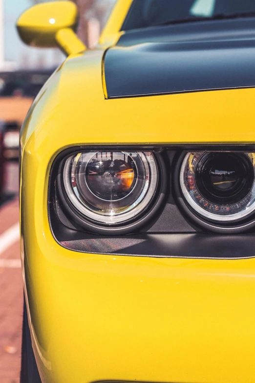 a close up of the headlights of a yellow car, a picture, by Etienne Delessert, pexels contest winner, photorealism, muscle cars, beautiful light big eyes, based on bumblebee, bright halo