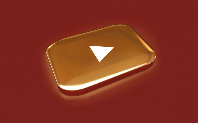 a shiny gold youtube button on a red background, by Ludovit Fulla, trending on polycount, video art, on a reflective gold plate, triforce, golden-hour, iphone video