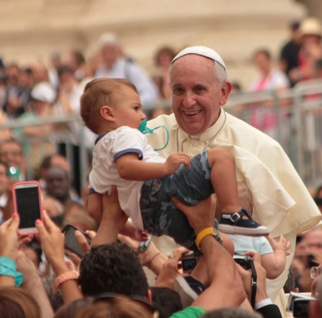 a man holding a baby in front of a crowd of people, inspired by Francis Helps, shutterstock, official photo, robot pope, 1 6 x 1 6, 3127318783