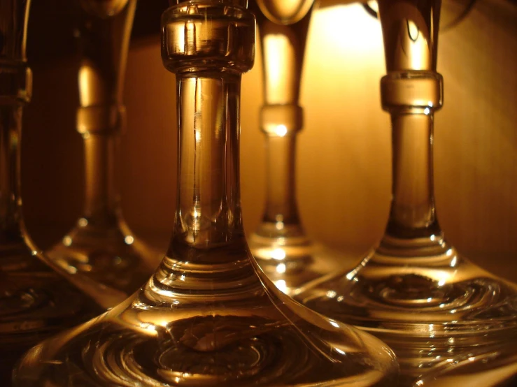 a group of wine glasses sitting on top of a table, by Andrew Domachowski, flickr, depth detail, long neck, amber, refraction lights