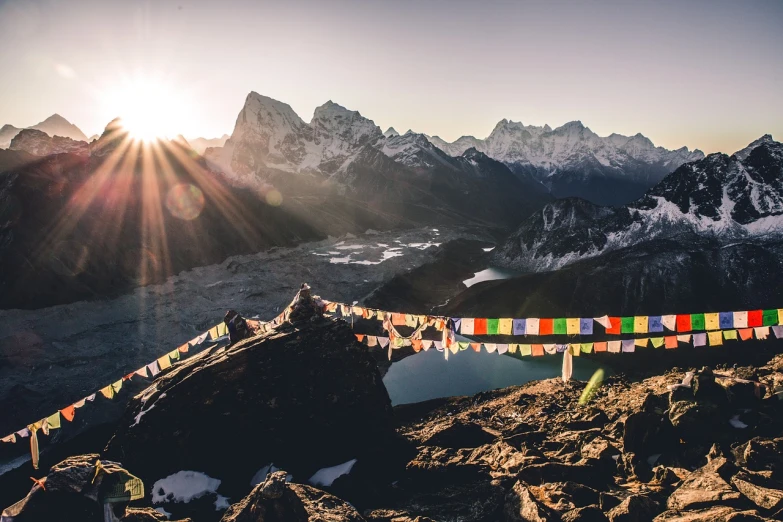 a group of people standing on top of a mountain, by Sebastian Spreng, unsplash contest winner, prayer flags, mountain lake, sun rises between two mountains, 4k high res