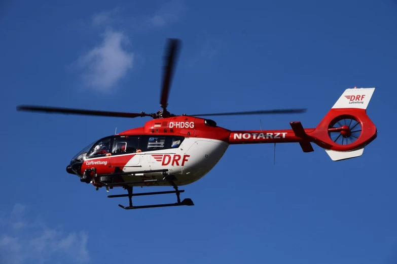 a red and white helicopter flying through a blue sky, by Hans Schwarz, hurufiyya, # de 9 5 f 0, aorta, rossier, 24 35 mm