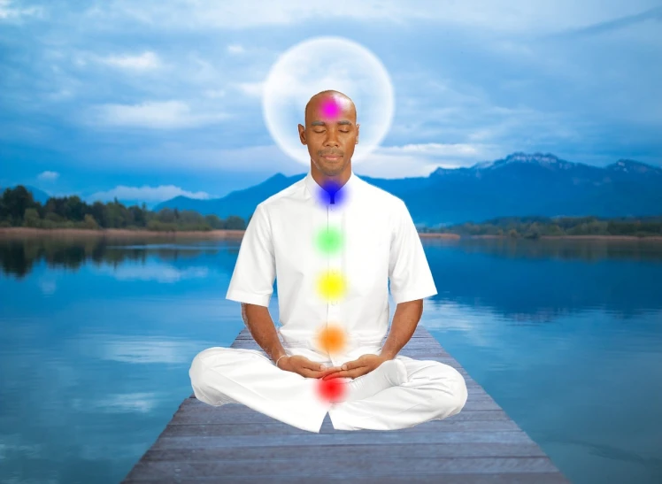 a man sitting on a dock in front of a body of water, a portrait, shutterstock, metaphysical painting, chakra diagram, wearing white robes, high res photo, jemal shabazz