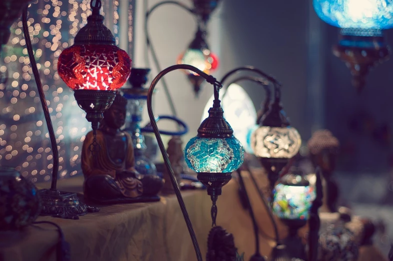 a table topped with lots of different colored lights, a tilt shift photo, arabesque, beautiful lit lamps, blue colors with red accents, vintage color photo, hand made