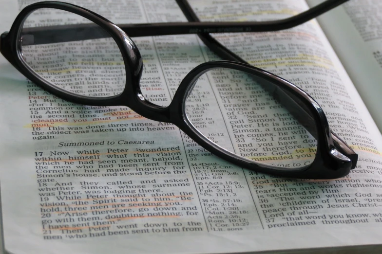 a pair of glasses sitting on top of an open book, biblical image, up close image, stems, readable