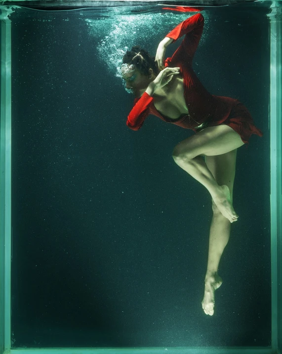 a woman in a red dress is under water, inspired by Annie Leibovitz, in a jumping float pose, akali, teal silver red, deep green