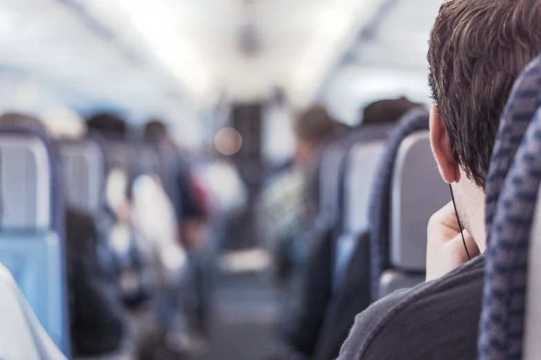 a man talking on a cell phone while sitting in an airplane, a picture, by Adam Marczyński, shutterstock, haze over the shoulder shot, blurred detail, banner, audience