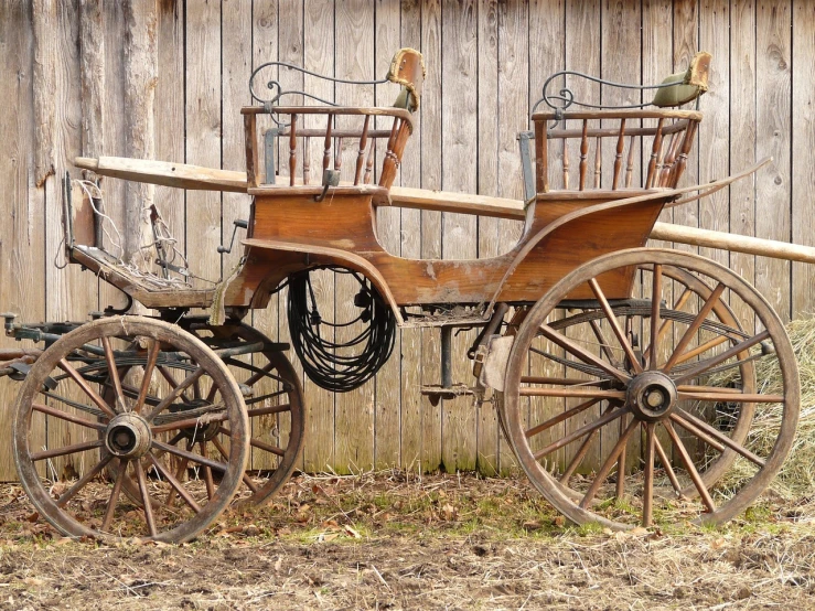 a horse drawn carriage sitting in front of a wooden fence, shutterstock, folk art, under repairs, vintage - w 1 0 2 4, old furnitures, old car