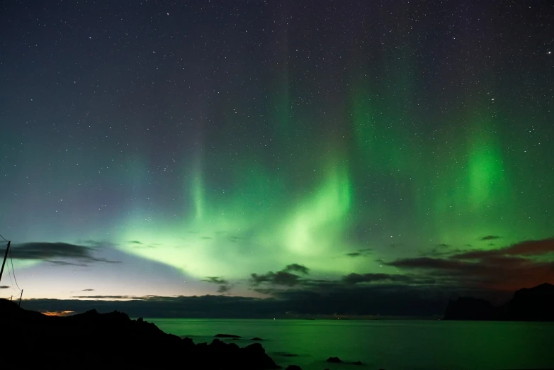 a green and purple aurora bore over a body of water, romanticism, looking onto the horizon, istock, niels otto møller, dancing lights