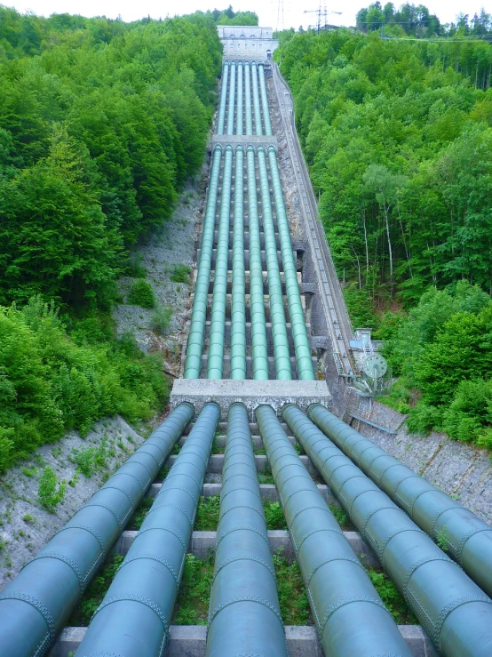 a bunch of pipes that are going down a hill, a photo, by Stefan Gierowski, shutterstock, wall of water either side, full of greenish liquid, perfect symmetrical image, stock photo