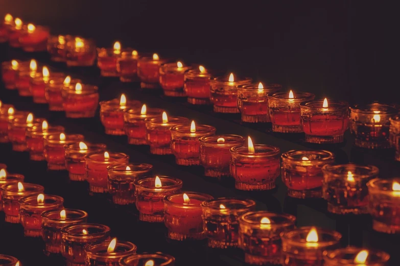 a group of lit candles sitting on top of a table, a picture, pexels, digital art, dark oranges reds and yellows, funeral, in a row, instagram post