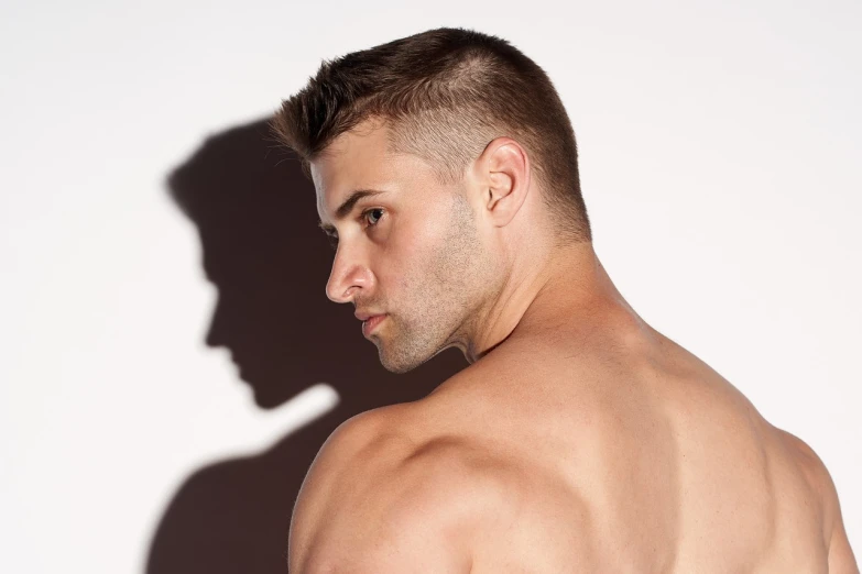 a shirtless man standing in front of a white wall, shutterstock, close - up profile face, undercut haircut, backlight photo sample, man turning into pony